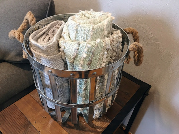 Gray and blue blankets with tassels in galvanized metal basket with rope handles industrial