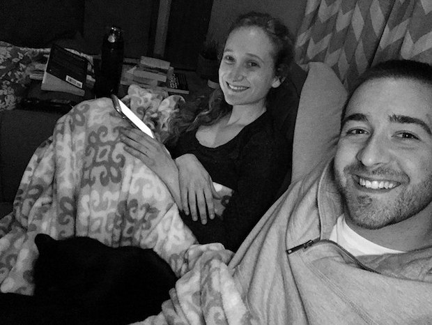 Couple cuddling on the couch with cat in black and white