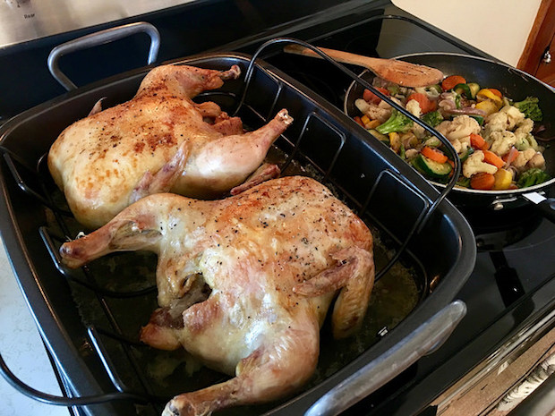 Two roasted rotisserie chickens with sautéed vegetables