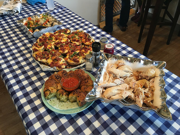 Table with chicken, parmesan bread, twice baked potatoes, horseradish, beet horseradish, and sautéed vegetables 