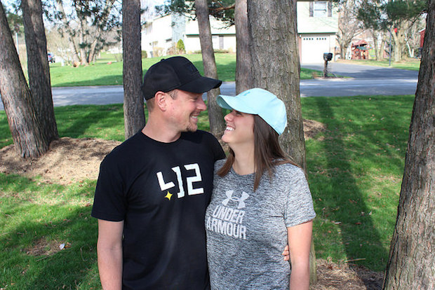 Young couple smiling at each other under shade of trees outside