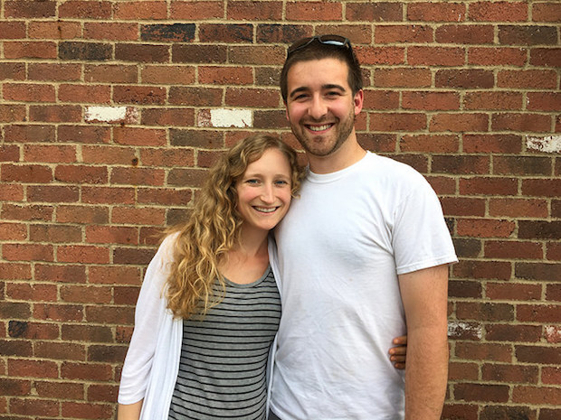 Couple smiling against brick wall