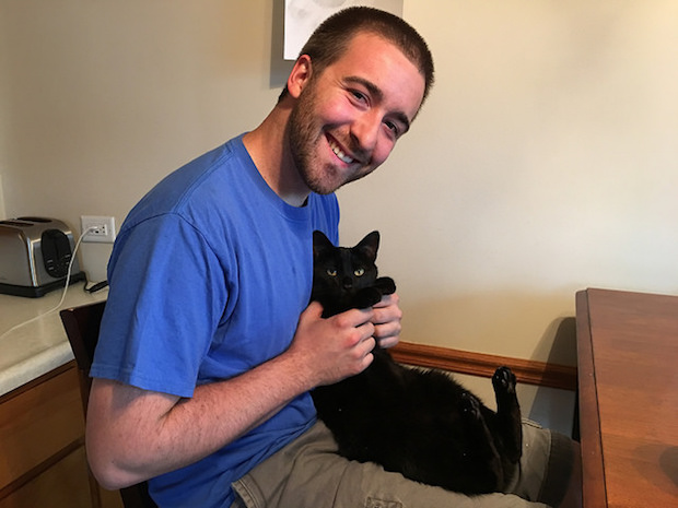 Guy holding cat and cat's paws on his lap