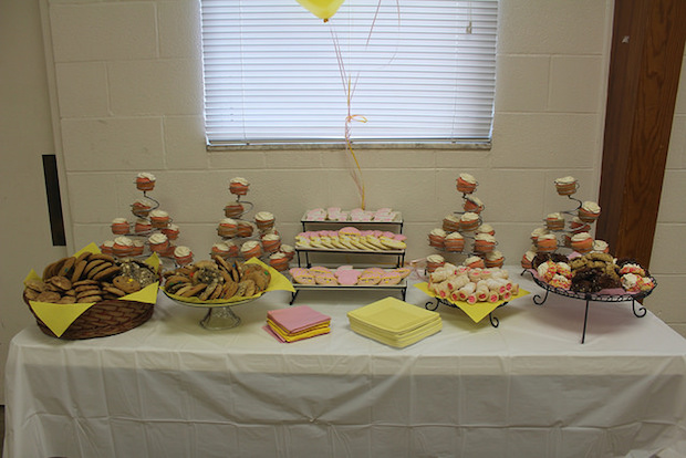 Baby shower dessert table for baby girl with cupcakes and decorated cookies pink and yellow