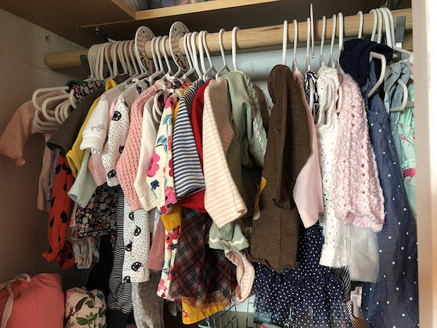 Baby girl closet with clothes and wood bars