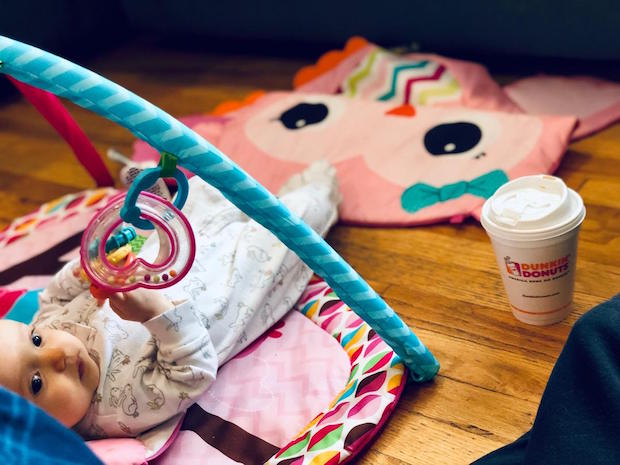 Baby on play mat with Dunkin Donuts coffee