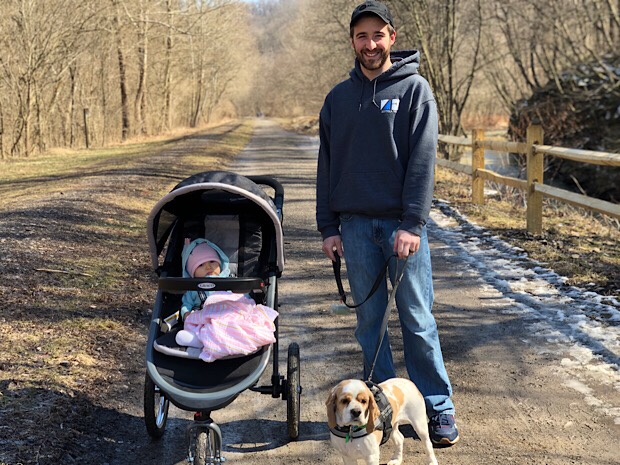 Dad with cocker spaniel and baby on trail with jogging stroller