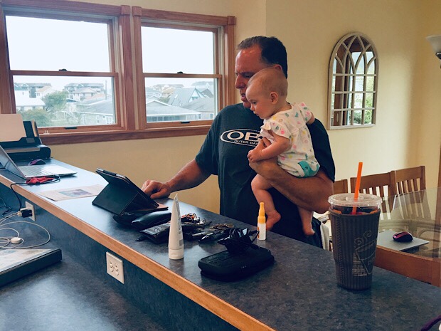 Grandfather holding baby girl and looking at computer