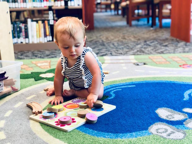 Baby girl doing puzzle at library