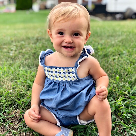 Baby girl smiling while sitting in grass