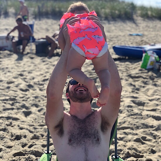 Dad holding baby in he air on the beach