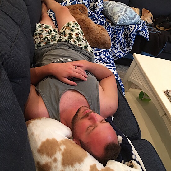 Guy laying on couch with three dogs