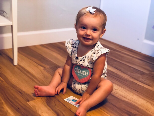 Baby girl sitting up and smiling 11 months