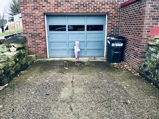 Toddler standing in front of garage