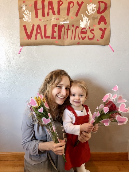 Mom and daughter with Valentines Day sign and flowers
