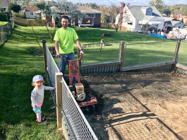 Dad and daughter tilling garden