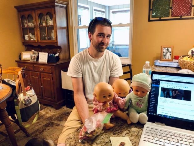 Guy sitting with three baby dolls