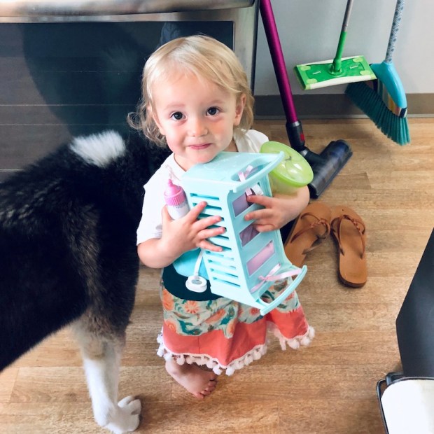 Toddler smiling while holding baby doll crib