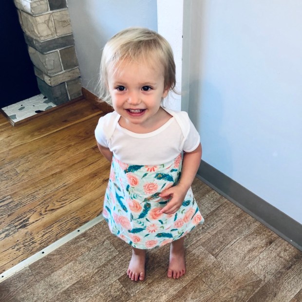 Toddler in homemade hand-sewn dress smiling 