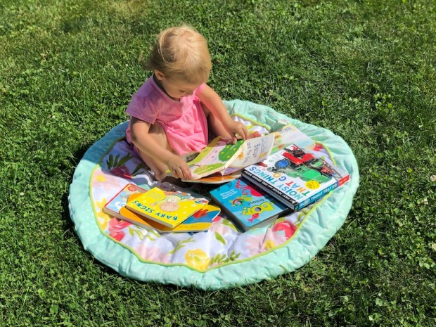 Toddler reading books in grass