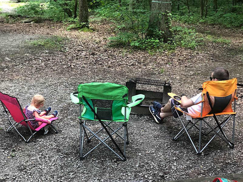 Father and toddler sitting by campfire