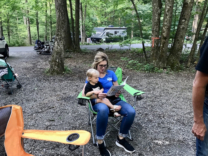 Toddler and Grandma reading books while camping
