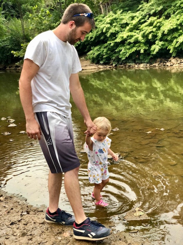 Dad and toddler walking by creek