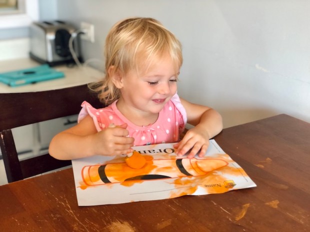 Toddler painting with orange paint