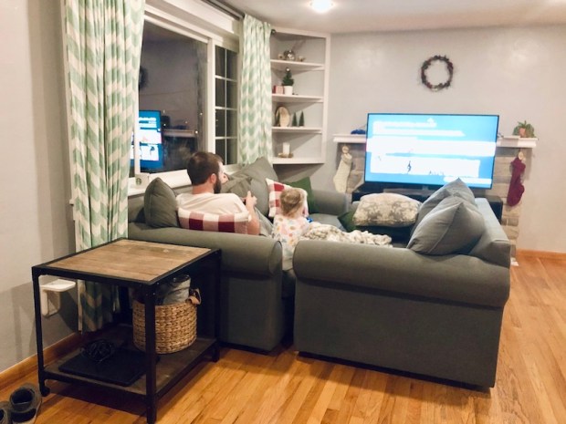 Dad and toddler watching TV with couches pushed together