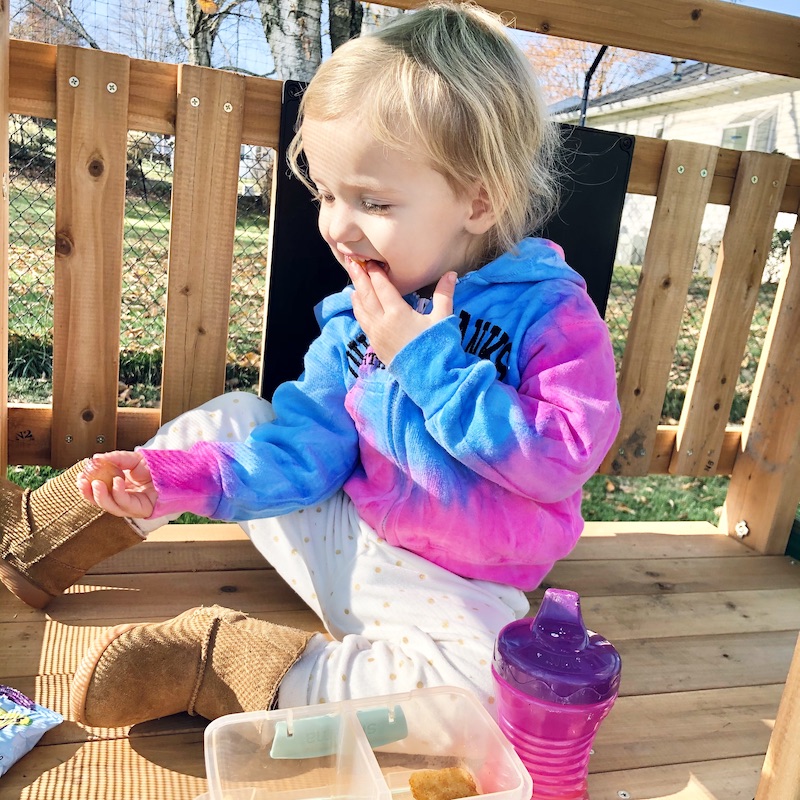 Toddler eating on top of swing set