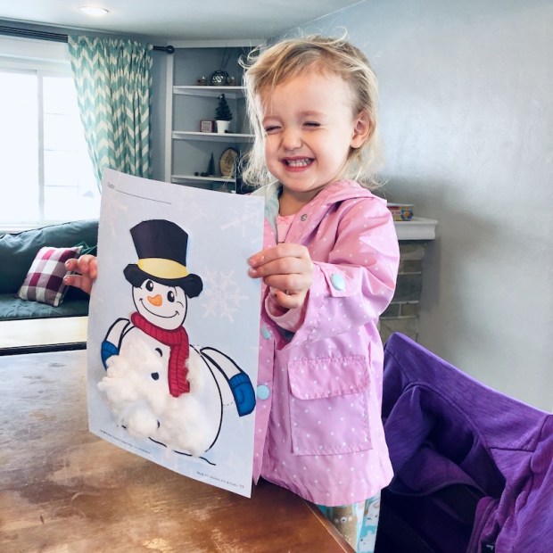 Toddler holding up snowman craft