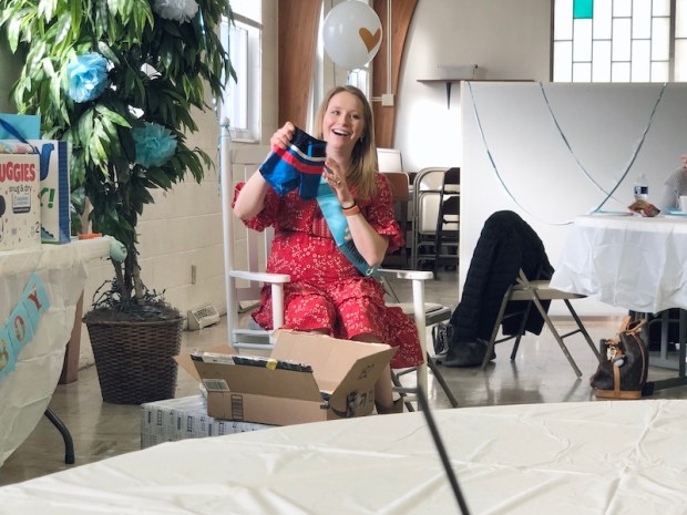 Mom to be opening gifts at baby shower for boy