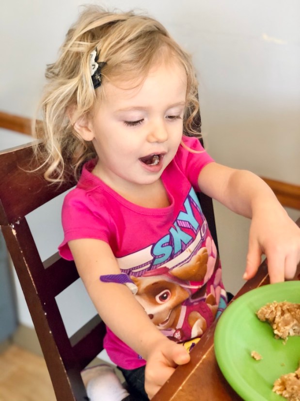Toddler eating snacks after bloodwork with purple bandage