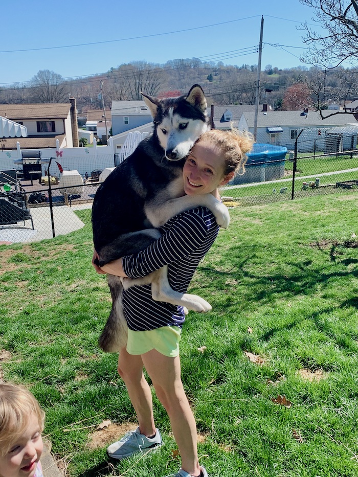 Girl holding husky like a child