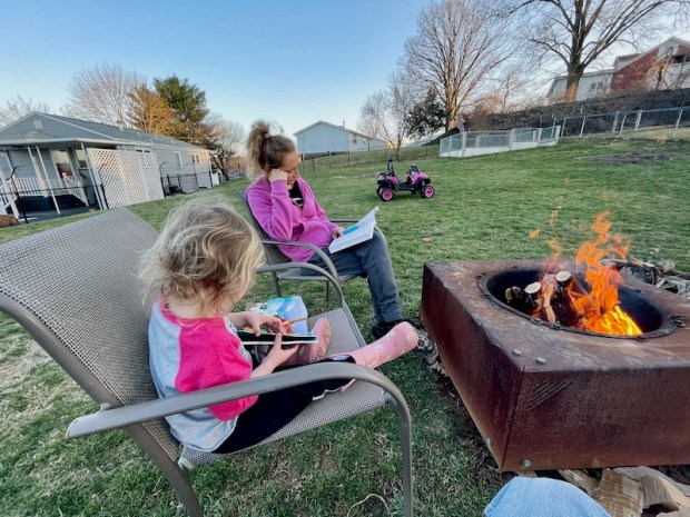 Mom and daughter reading by a bonfire