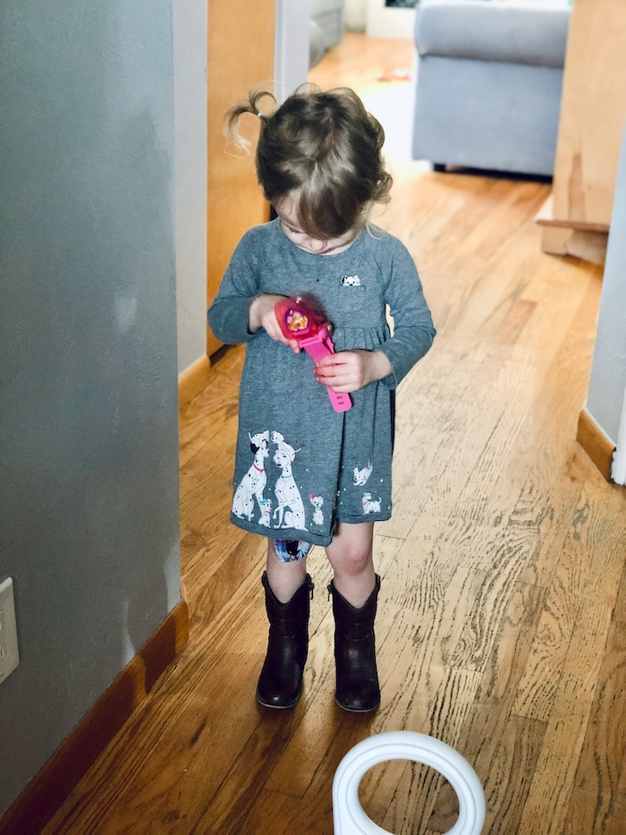 Toddler wearing 101 Dalmatians dress and cowboy boots while looking at Skye Paw Patrol watch.