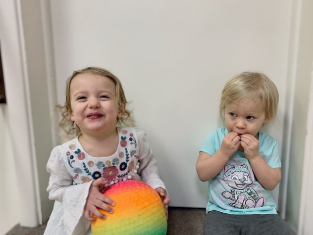 Toddler girls sitting together with ball