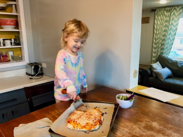 Toddler cutting homemade pizza