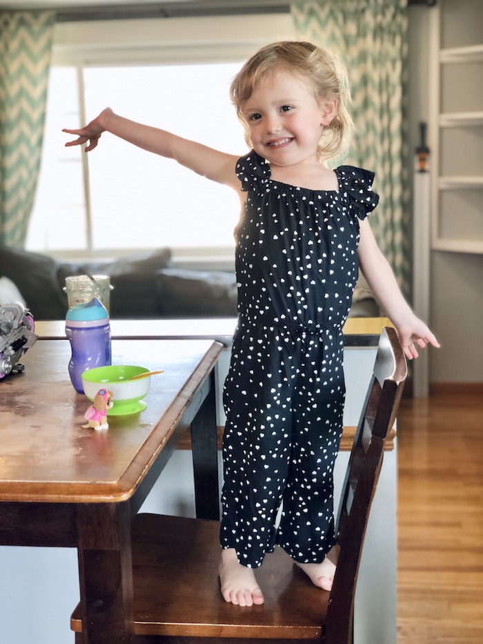 Toddler girl wearing black jumpsuit with white hearts