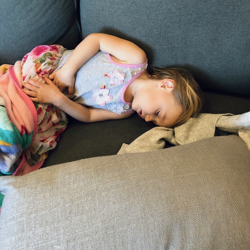 Toddler laying on couch sick with stomach bug.