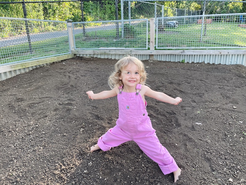 Toddler playing in dirt in Carhartt overalls