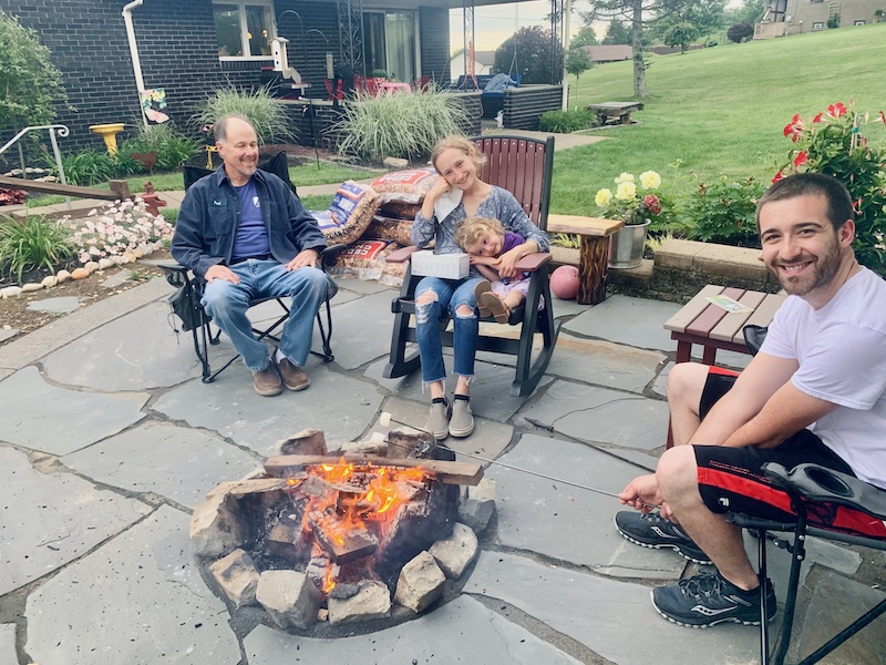 Family sitting by fire pit with s'mores