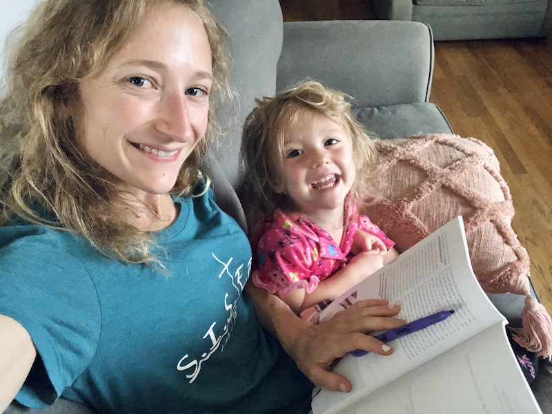 Mom and toddler daughter reading Bible study together on couch