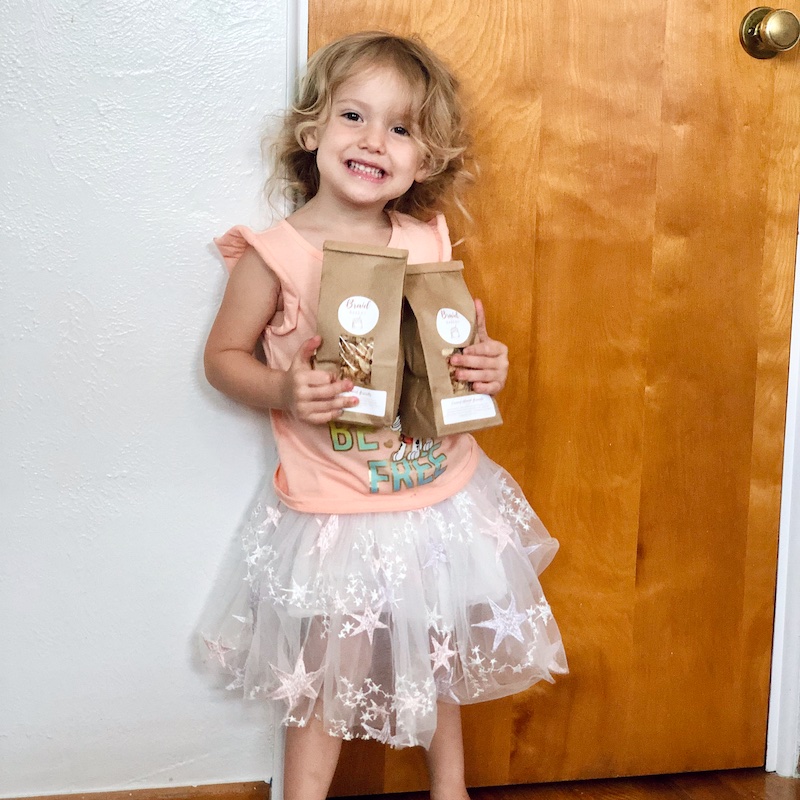 Toddler holding bags of granola from Etsy shop.