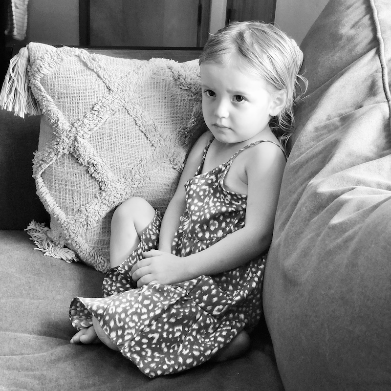 Black and white picture of toddler girl sitting on couch