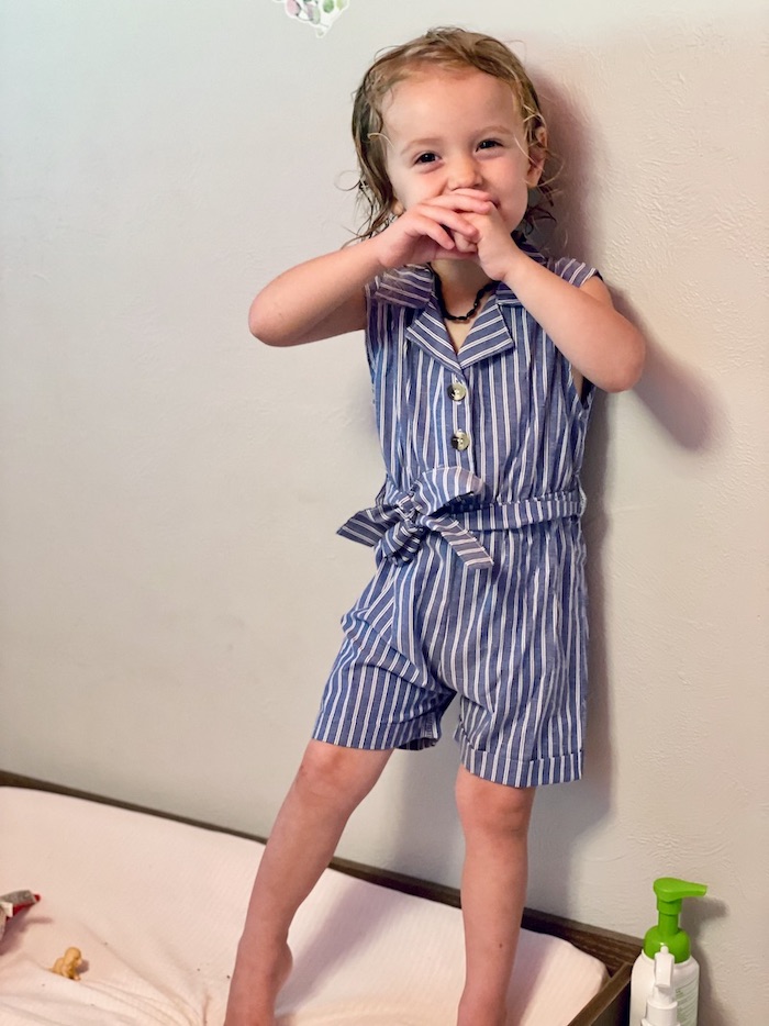 Toddler girl wearing blue and white striped romper