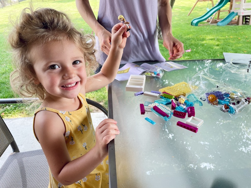 Toddler playing with LEGO Friends set outside
