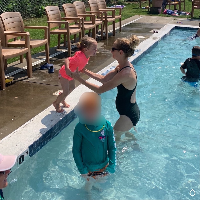 Mom catching toddler girl as she jumps in pool