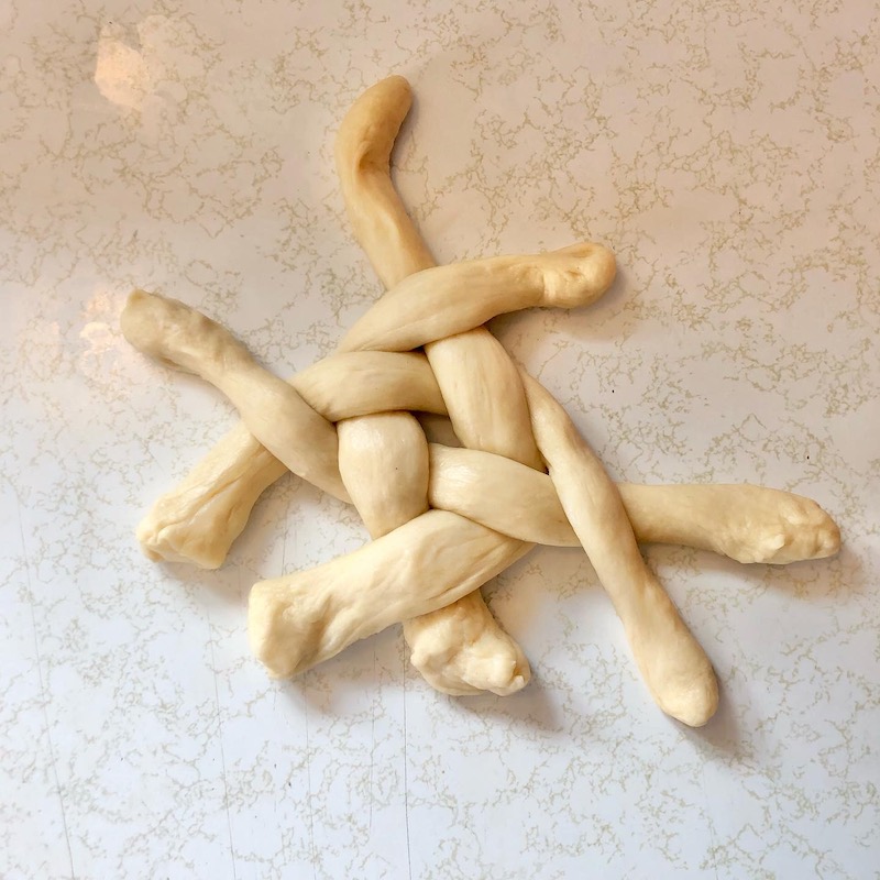Challah bread dough being woven and braided