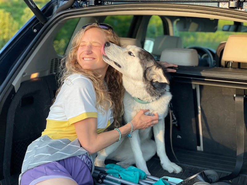 Girl sitting with SIberian husky licking her face